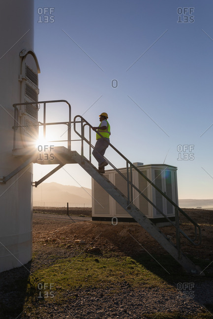 Engineer climbing up the stairs of a wind mill at a wind farm