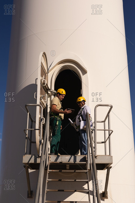 Engineers standing at the entrance of wind mill at a wind farm