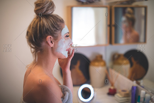 Woman applying facial cream in bathroom at home