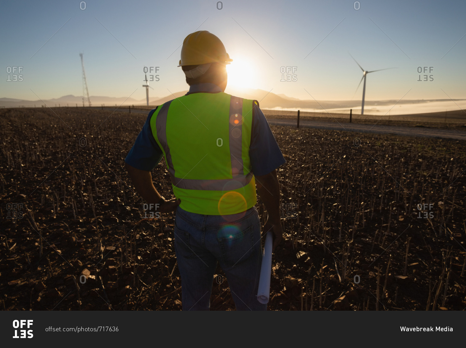 Rear view of engineer standing at a wind farm
