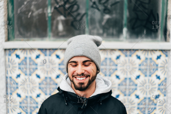 Cheerful excited tourist man standing at wall with blue tiles tiles