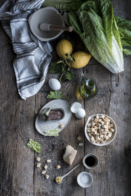 Bunch of various ingredients for delicious dish lying on old lumber tabletop near mortar and pestle