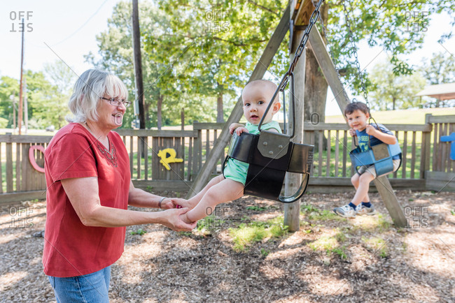 Grandmother Pushing Baby In Swing At Park Stock Photo Offset