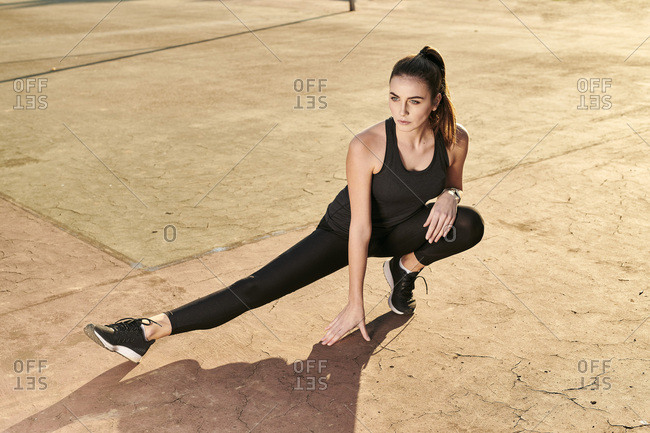 Sportive woman stretching leg on concrete floor