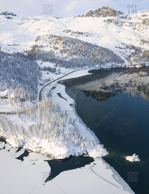 Aerial panoramic view of road around frozen Lake Sils, Plaun da Lej, Maloja Region, Canton of Graubunden, Engadine, Switzerland, Europe (Drone)