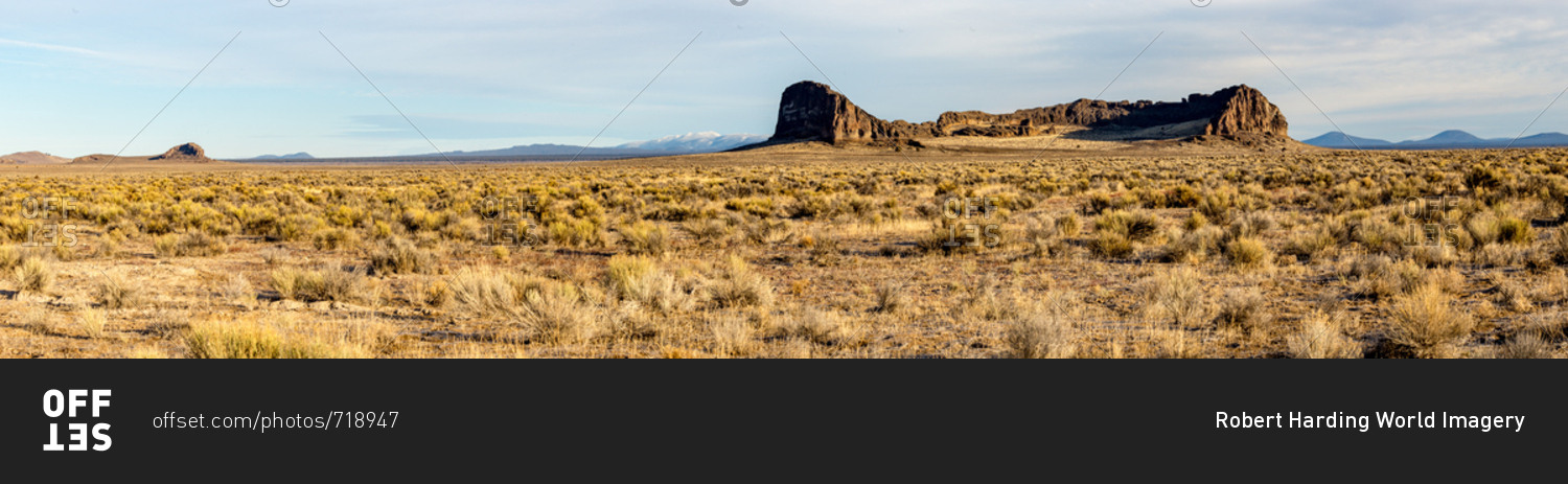 A panorama of sagebrush and rock formations in front of mountains, Oregon, United States of America, North America