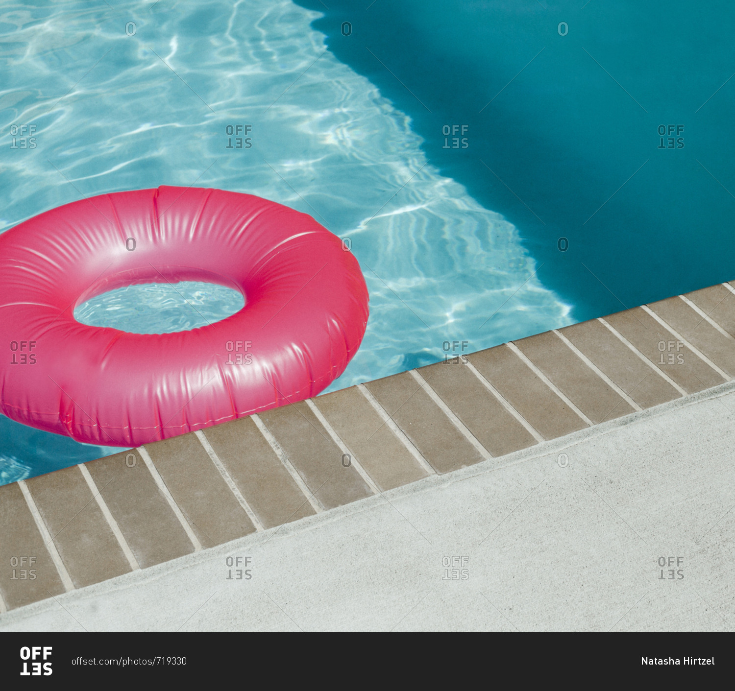 Pink inner tube with the edge of the pool visible stock photo OFFSET