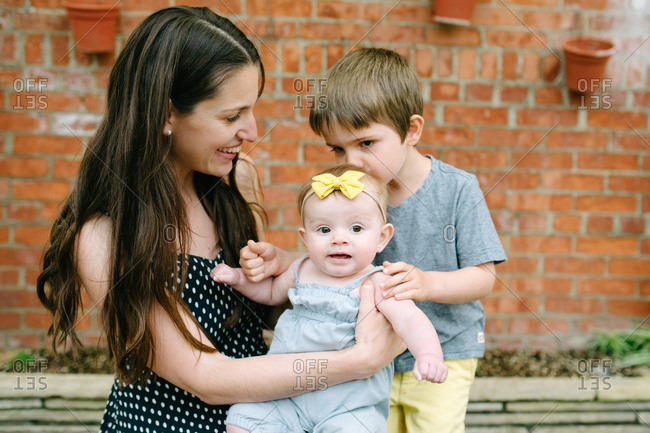 Brother kissing baby while mother holds her