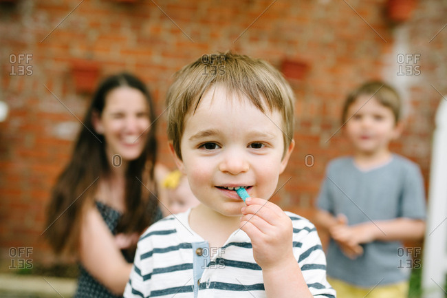 Boy eating candy with family in background