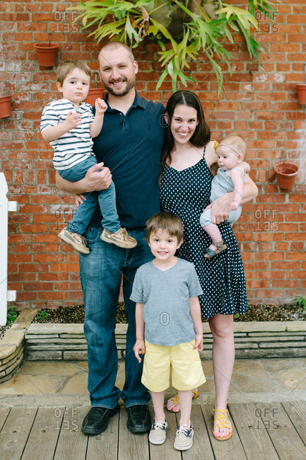Happy family in front of a brick wall at a botanical garden