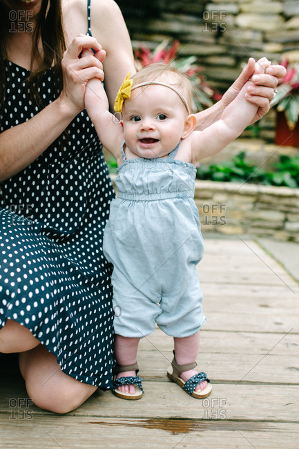 Mother holding baby by hands in a botanical garden