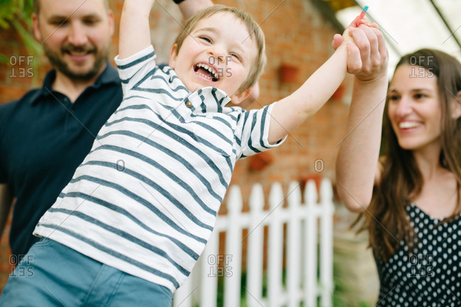 Mother and father swinging little boy