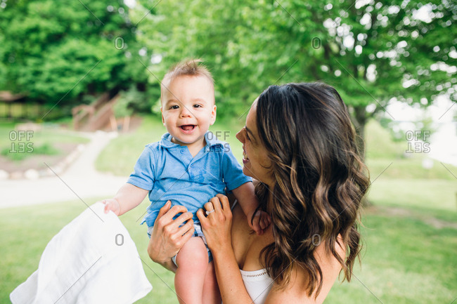 Mother holding happy baby boy outdoors