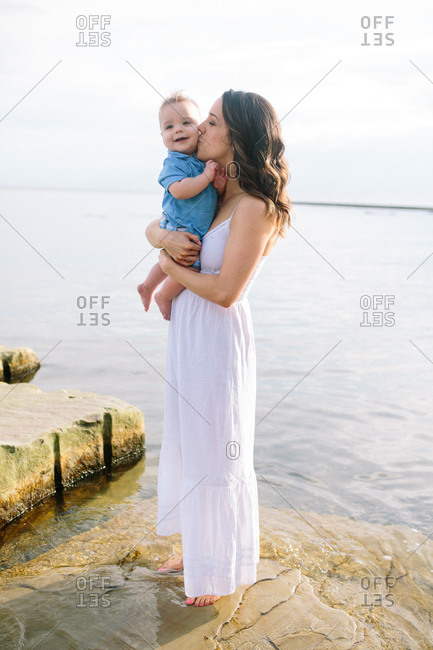 Father holding happy baby's hands on a beach