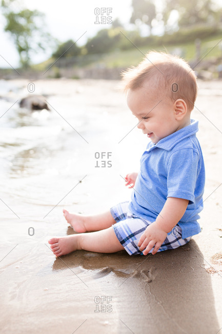 Happy baby sitting in sand on a beach