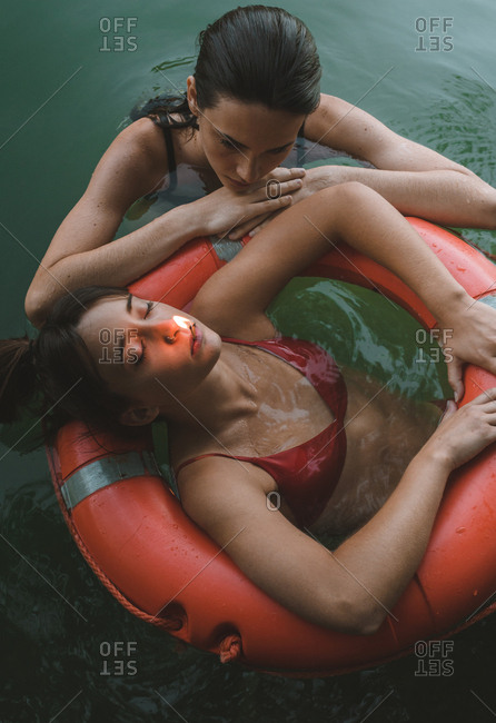 Overhead view of a couple of girls floating on lifebelt with a match lit in their mouths