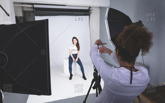 Female photographer clicking photos of model in photo studio