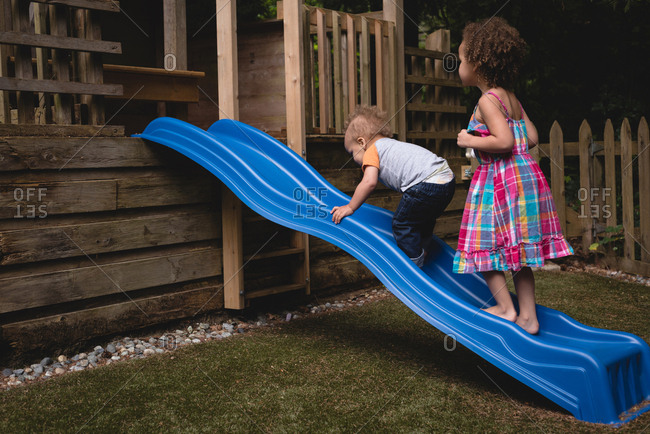 Mixed race boy sliding down slide in playground - Stock Photo - Dissolve