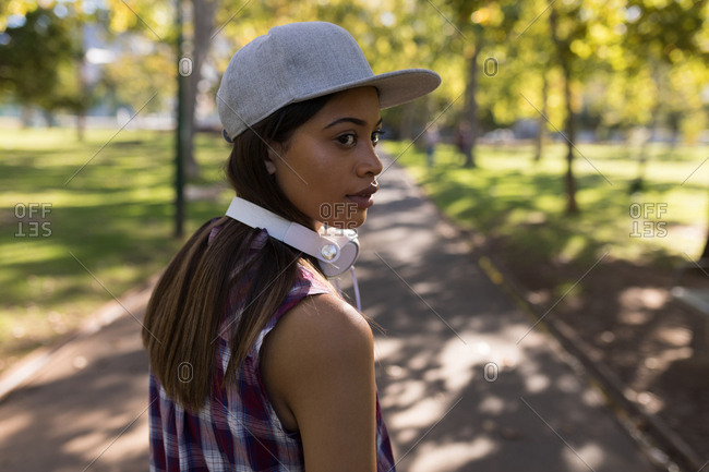 Woman with headphones looking over shoulders in the park