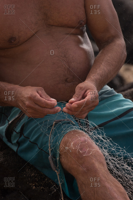 Mid section of fisherman holding fishing net