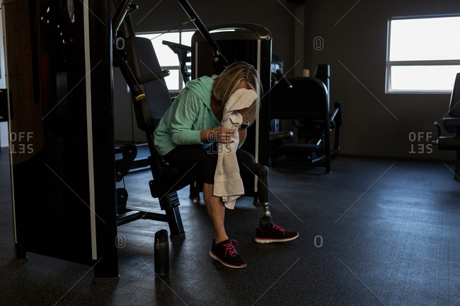 Disabled woman cleaning her face with towel in the gym