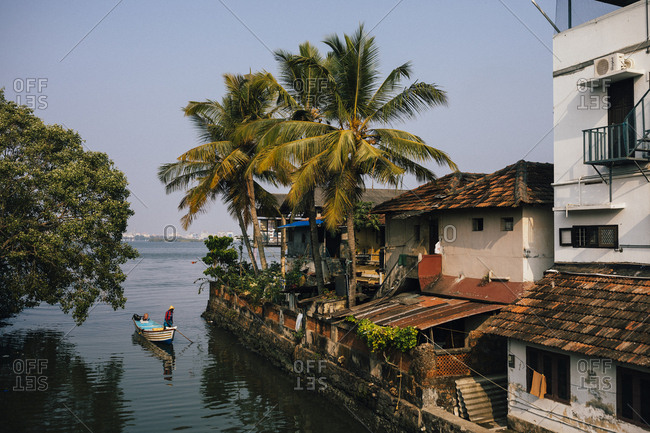 Fort Kochi, India - February 12, 2018: A fishing boat makes its way through a small neighborhood canal in Fort Kochi