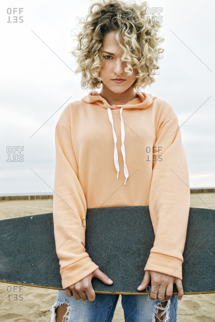 Young Woman With Curly Blond Hair Wearing Pink Hoodie And Ripped