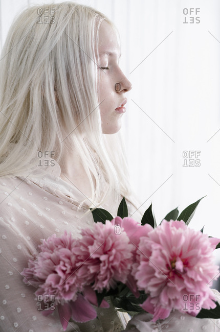 Side View Of Woman With Bleach Blonde Hair Holding Pink Flower