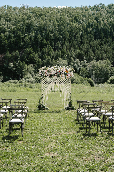 Wedding ceremony with arbor and wooden chairs