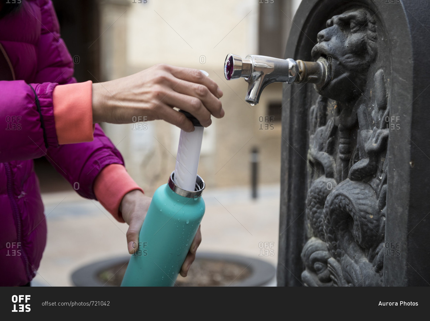 Woman filling bottle with water from water fountain, Cornudella de Montsant, Catalonia, Spain