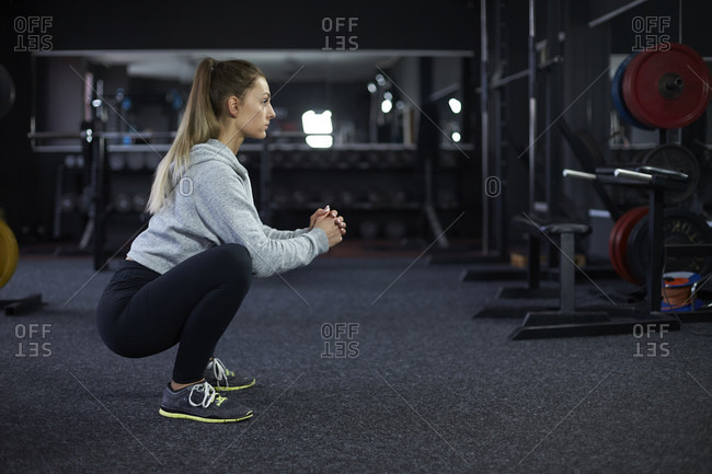 Side view shot of woman doing squats in gym