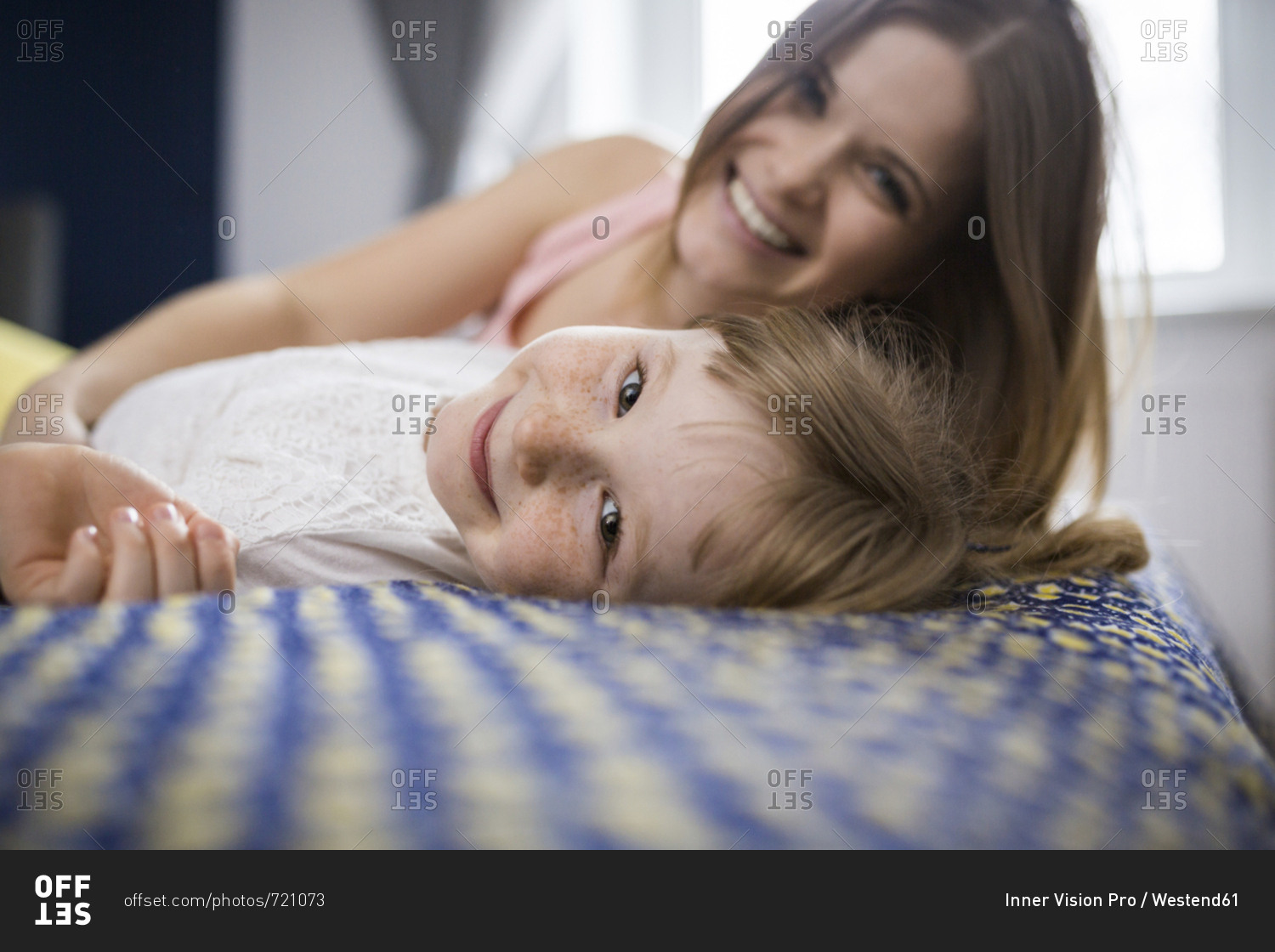 Happy mother and daughter lying on bed
