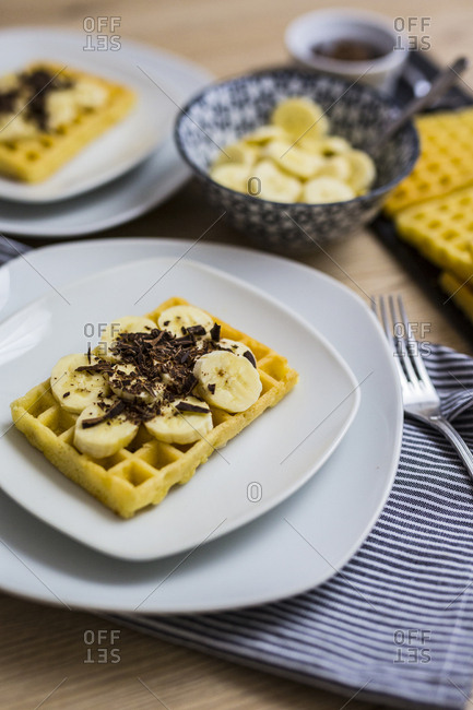 Waffle garnished with banana and chocolate shaving on plate