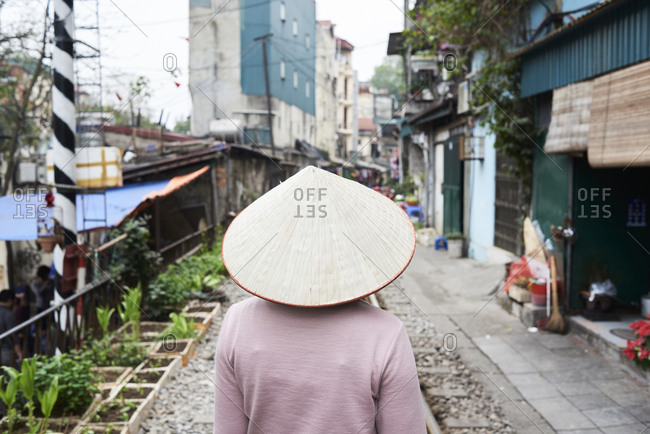 Faceless Vietnamese woman walking on the train street wearing traditional hat, Hanoi, Vietnam