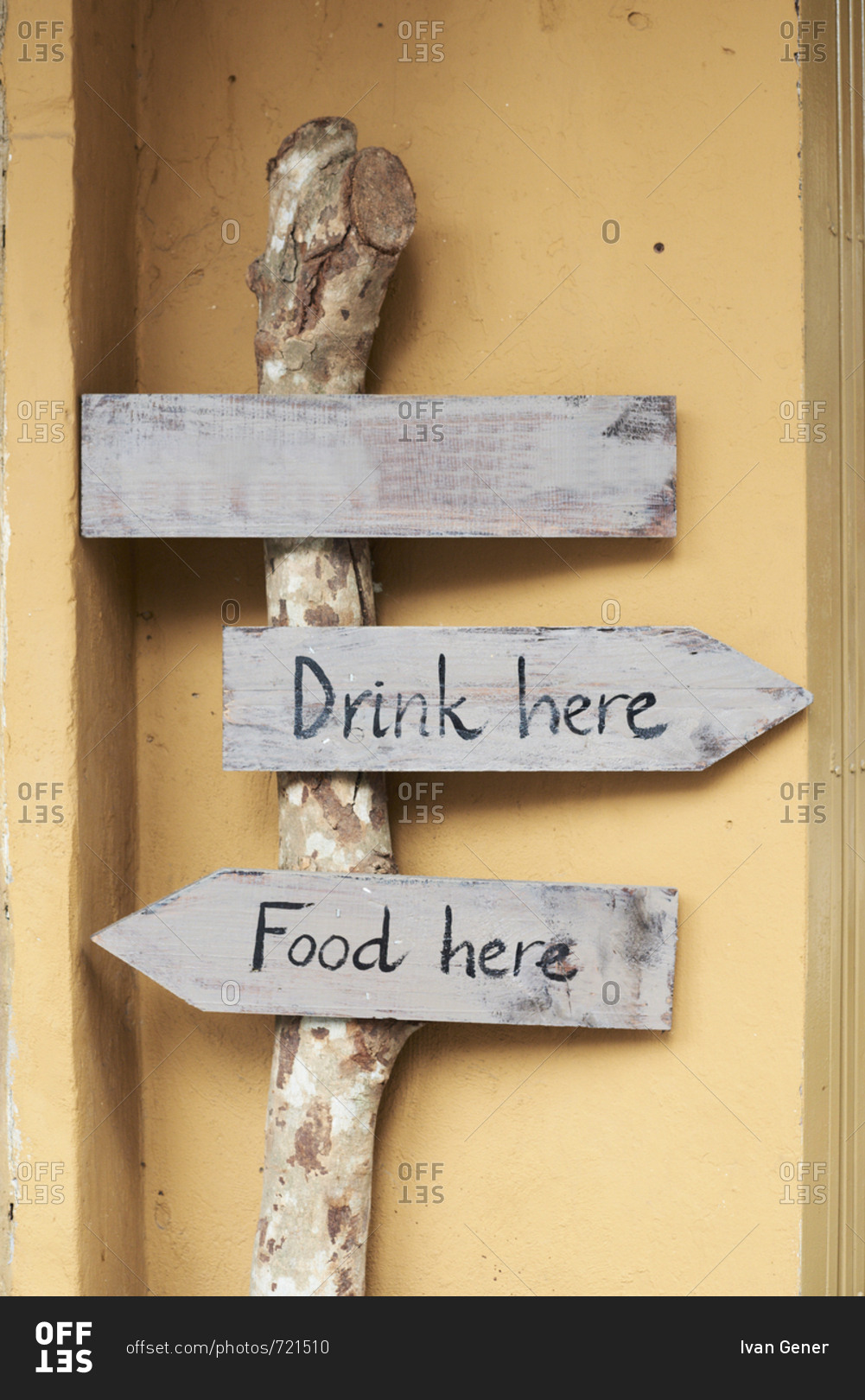 Hand-written wood sign boards with messages of drink and food here pointing in opposite directions