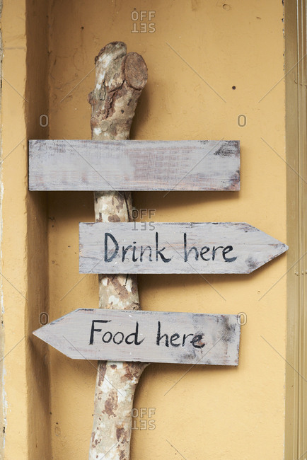 Hand-written wood sign boards with messages of drink and food here pointing in opposite directions