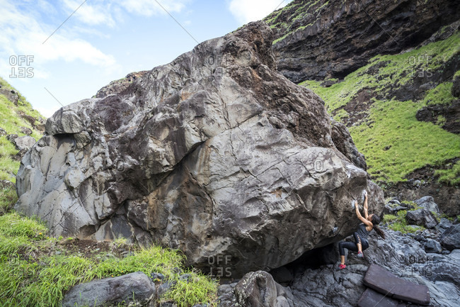 Distant view of adventurous woman climbing boulder, Maui, Hawaii Islands, USA