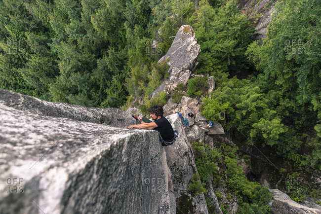 View from above of adventurous rock climber climbing challenging cliff, Squamish, British Columbia, Canada