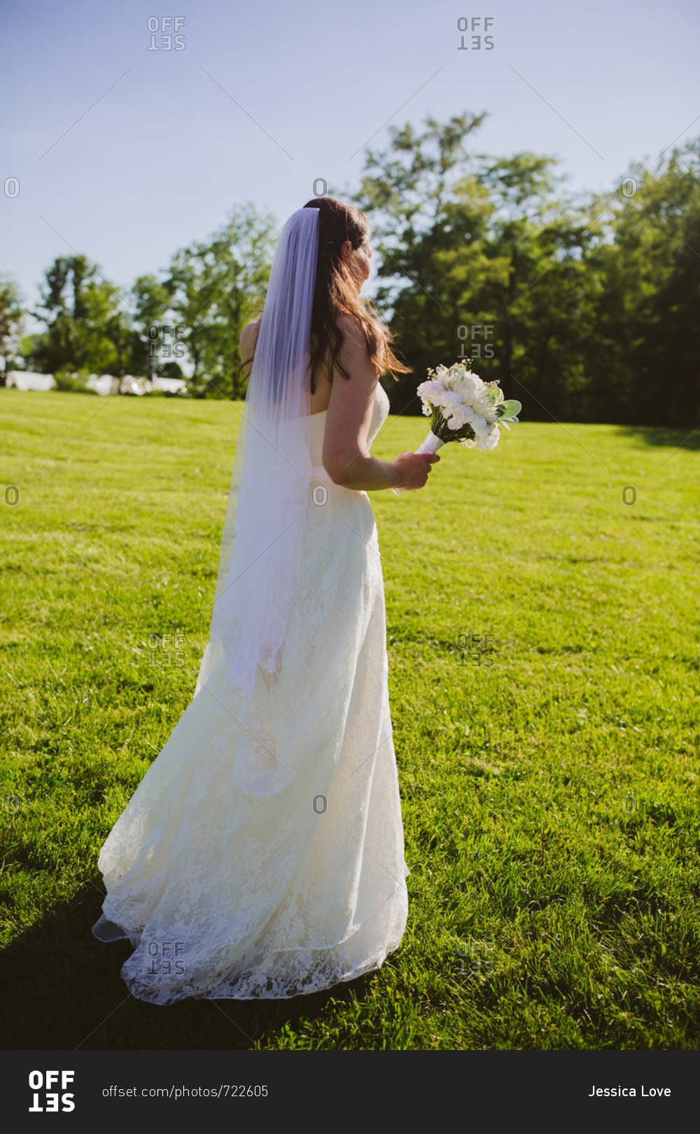 Back view of bride holding bridal bouquet at outdoor farm wedding