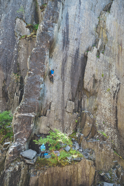 Rock climber climbing slate walls at Dinorwic Slate Quarry in Llanberis, Snowdonia, UK