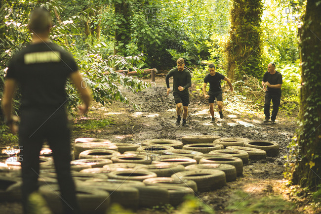 Fit men training over tires obstacle course at boot camp