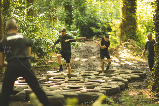 Fit men training over tires obstacle course at boot camp