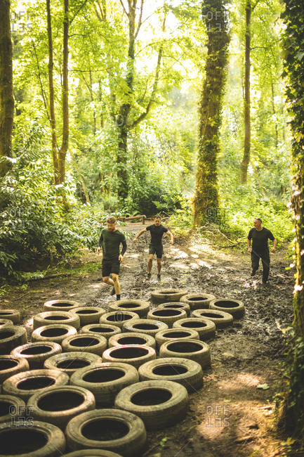 Fit men training over tires obstacle course at boot camp