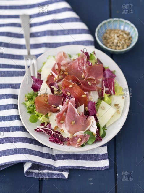 A mixed lettuce with melon, ham and sunflower seeds