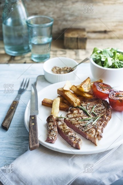 Steak with grilled tomatoes, chips and salad
