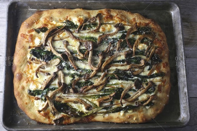 Pan pizza with mushrooms and spinach on a baking tray