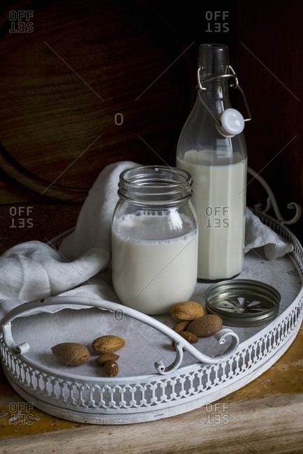 Vegan almond milk in a flip-top bottle and a screw-top jar on a tray
