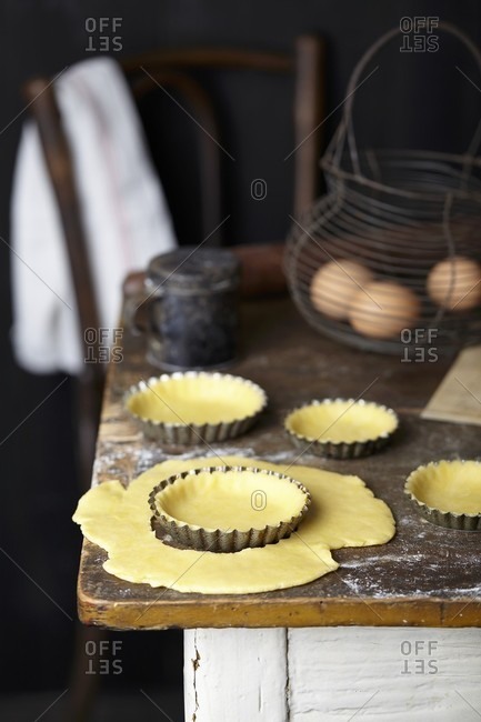 Shortcrust pastry for apple and frangipane tart in tart tins on a rustic kitchen table