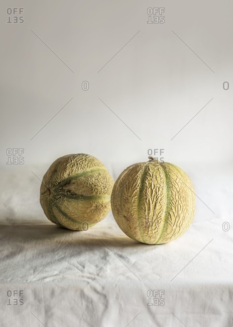 Two cantaloupe melons on a tablecloth