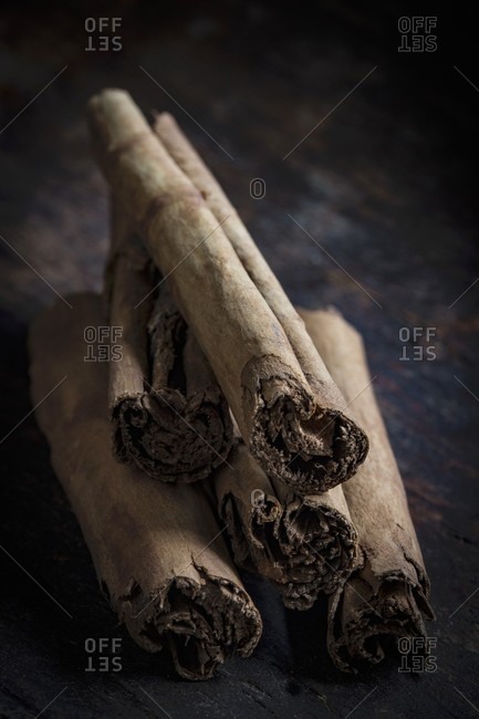 A stack of cinnamon sticks on a dark wooden table